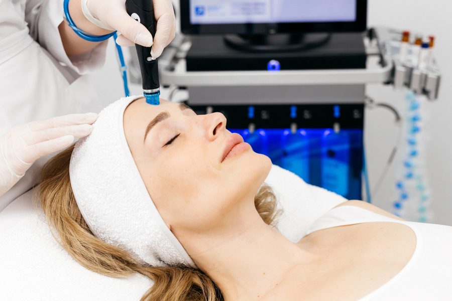 Female client receiving hydrafacial treatment in a modern cosmetology clinic