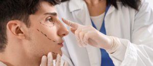 Young man with marked face visiting plastic surgeon in clinic
