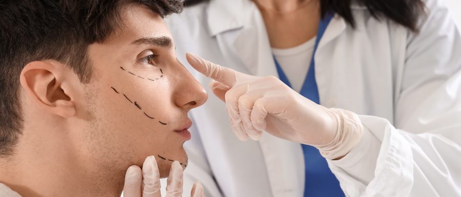 Young man with marked face visiting plastic surgeon in clinic